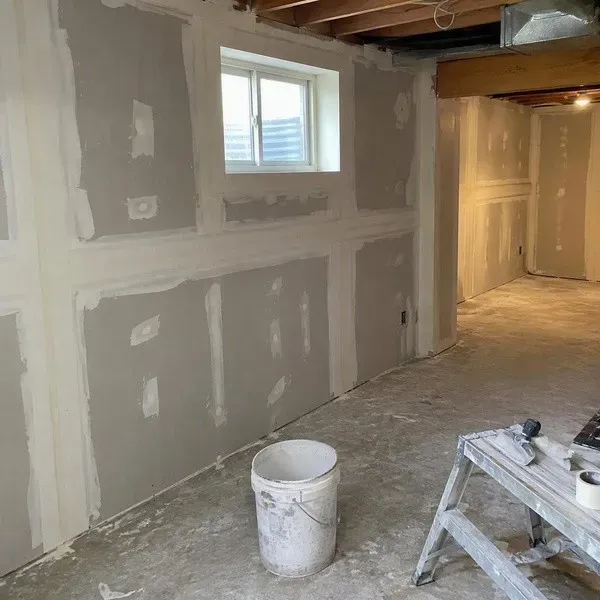 Freshly taped drywall seams across basement walls in a newer home