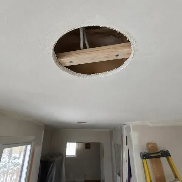 Backing strip installed inside a circular ceiling hole before patching