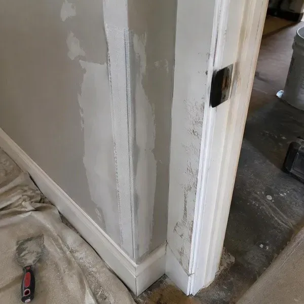 Corner bead drywall repair beside a scuffed doorway
