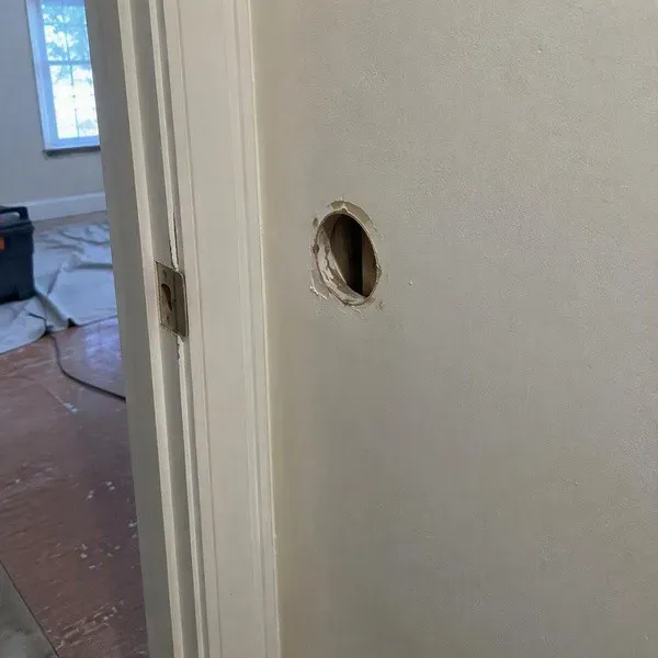 Small doorknob hole in a painted wall before rental turnover repair