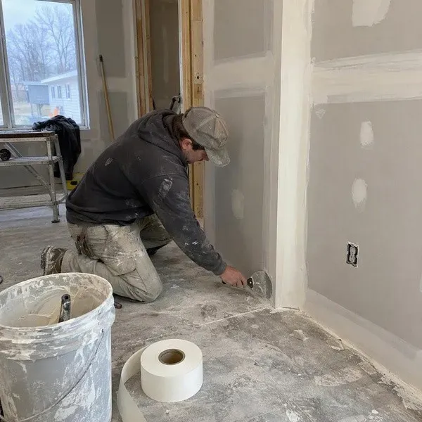 Drywall finishing contractor smoothing joint compound near the floor