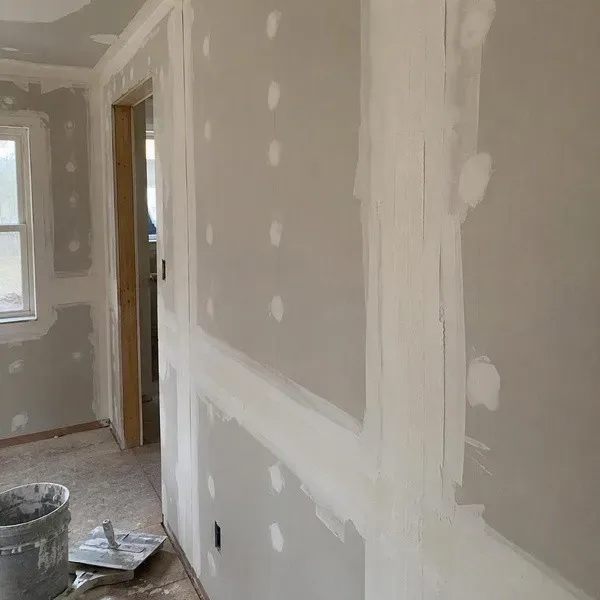 Drywall screw heads filled with compound beside taped seams