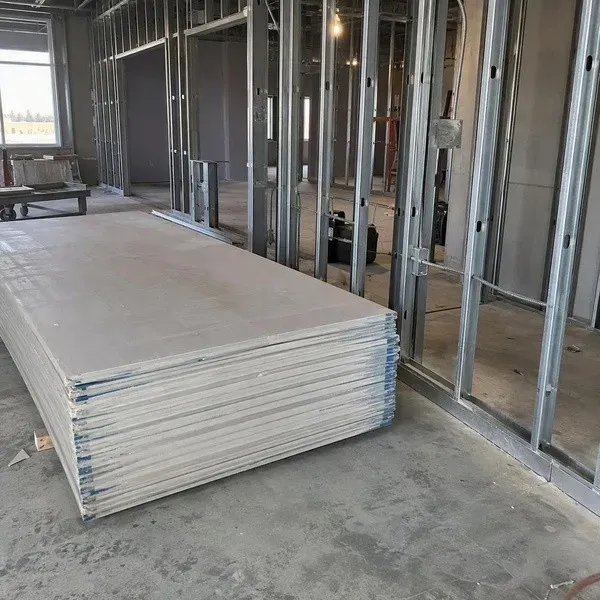 Drywall sheets stacked beside metal studs in a commercial office build-out