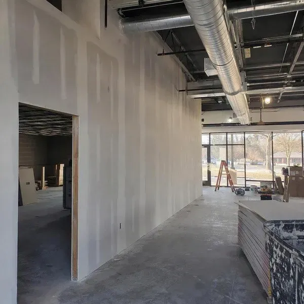 Retail space with exposed ductwork above new drywall before ceiling installation