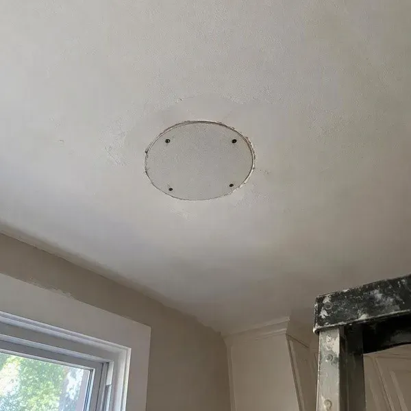 Round drywall plug fitted into an abandoned ceiling light opening